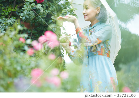 Senior Woman Holding A Parasol In The Garden Stock Photo