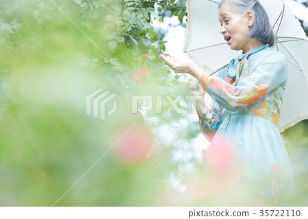 Senior woman holding a parasol in the garden 35722110