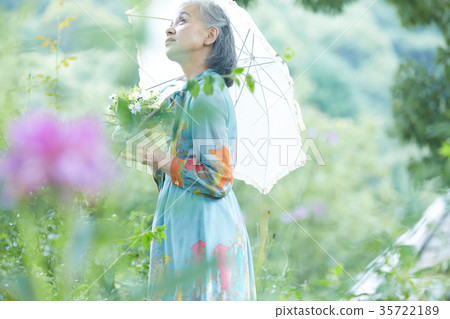 Senior Woman Holding A Parasol In The Garden Stock Photo