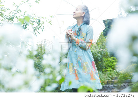 Senior woman holding a parasol in the garden Senior woman holding a parasol in the garden 35722272