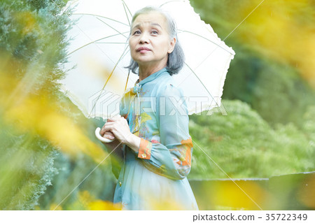拿著遮陽傘的資深婦女在庭院裡 35722349