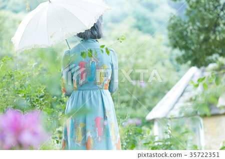 拿著遮陽傘的資深婦女在庭院裡 拿著遮陽傘的資深婦女在庭院裡 35722351