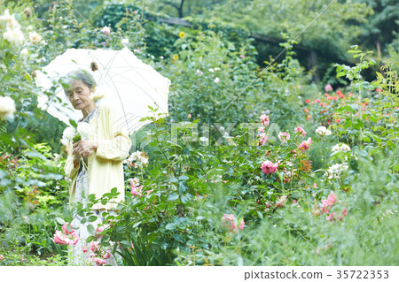 拿著遮陽傘的資深婦女在庭院裡 拿著遮陽傘的資深婦女在庭院裡 35722353