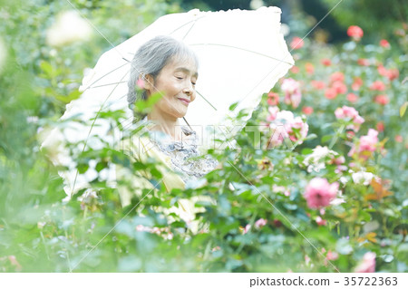 Senior woman holding a parasol in the garden 35722363