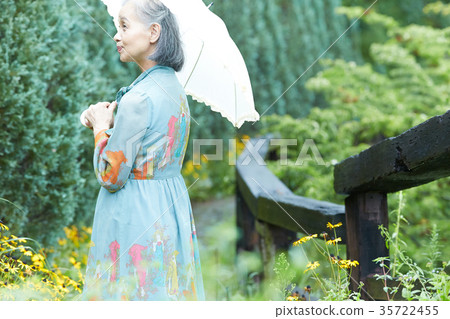 Senior woman holding a parasol in the garden 35722455