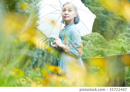 Senior Woman Holding A Parasol In The Garden Stock Photo