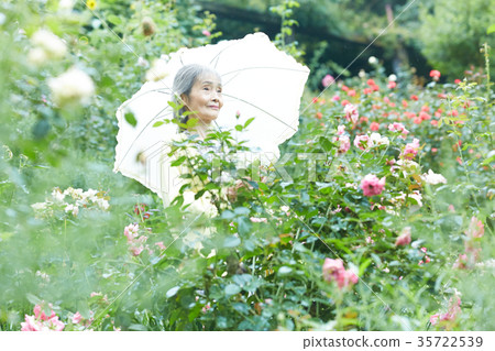 Senior Woman Holding A Parasol In The Garden Stock Photo