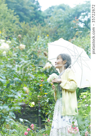 Senior Woman Holding A Parasol In The Garden Stock Photo