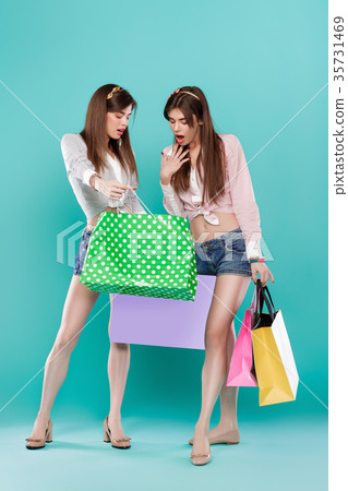 female twins with shopping bags on blue background female twins with shopping bags on blue background 35731469
