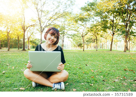 Young asian woman's legs on grass with open laptop 35731589