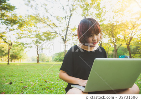 Young asian woman's legs on grass with open laptop 35731590