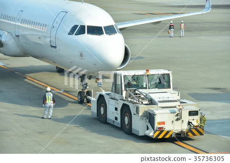 A passenger plane that is pushed by a towing tractor and departs 35736305