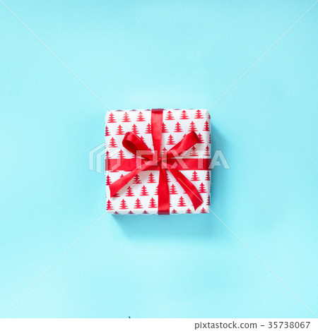 Christmas gift with red ribbon on blue surface.  35738067