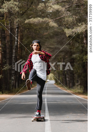 A young hipster in a cap and plaid shirt is riding 35739999