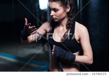 Young fighter boxer girl putting on hand bandage Young fighter boxer girl putting on hand bandage 35740373