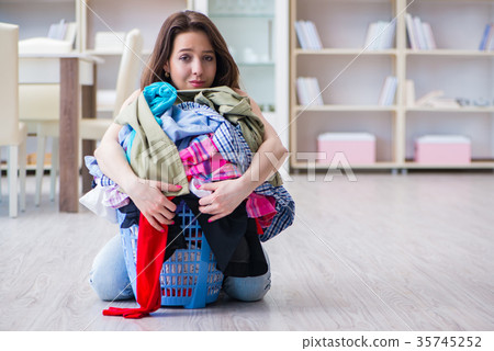 Stressed woman doing laundry at home 35745252