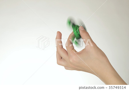 Hands of a teenage girl spin a green fidget 35749314