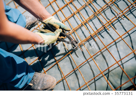 worker using pincers and steel wire to secure bars 35773131