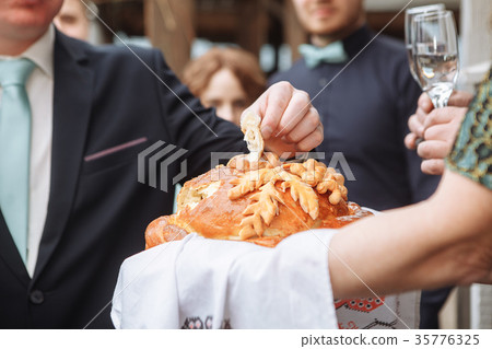 Groom holding slice of traditional wedding round Groom holding slice of traditional wedding round 35776325