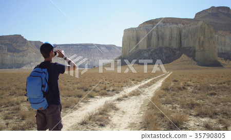 A young traveler drinks water against the rocks A young traveler drinks water against the rocks 35790805
