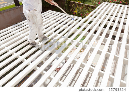 Professional Painter Rolling White Paint Onto The Top of A Home 35795834