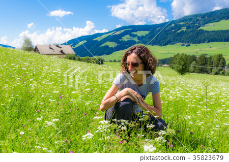 girl sitting on grass admiring flowers 35823679
