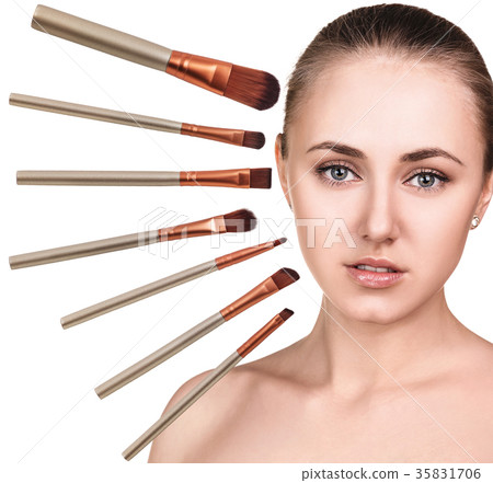 Woman's face surrounded by makeup brushes. 35831706