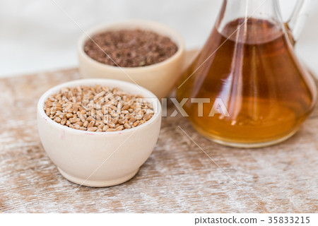 Wheat grains in wooden bowl and oil in decanter Wheat grains in wooden bowl and oil in decanter 35833215