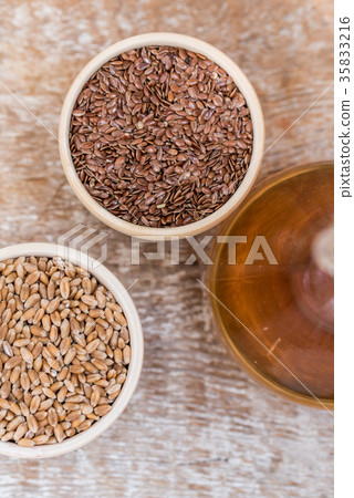 Wooden bowls with flax and wheat grain and oil 35833216