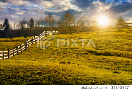 fence on grassy hillside in autumn at sunset 35848837