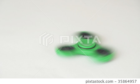 Green fidget spinner turns and stops on white 35864957