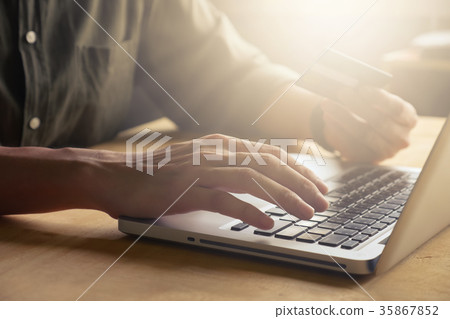 man holding credit card and using laptop man holding credit card and using laptop 35867852