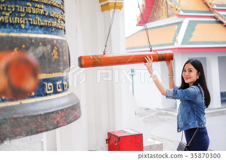 Woman ringing a bell in a Buddhist temple 35870300