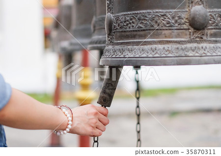 Woman ringing a bell in a Buddhist temple 35870311