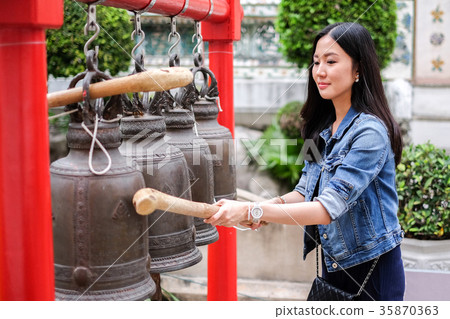 Woman ringing a bell in a Buddhist temple 35870363