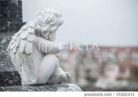 stoned angel sitting on tomb in a cemetery 35882231
