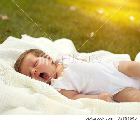 Baby yawing on the blanket on the grass Baby yawing on the blanket on the grass 35884609