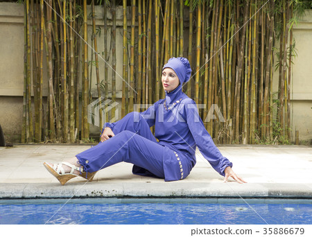attractive woman in a Muslim swimwear burkini sits 35886679