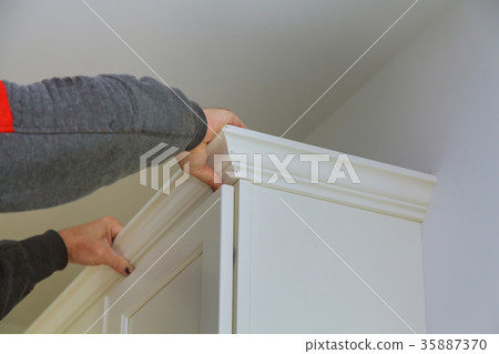 Carpenter brad using nail gun to Crown Moulding on kitchen cabinets 35887370
