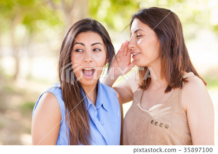 Two Beautiful Ethnic Twin Sisters Whispering Secrets Outdoors. Two Beautiful Ethnic Twin Sisters Whispering Secrets Outdoors. 35897100