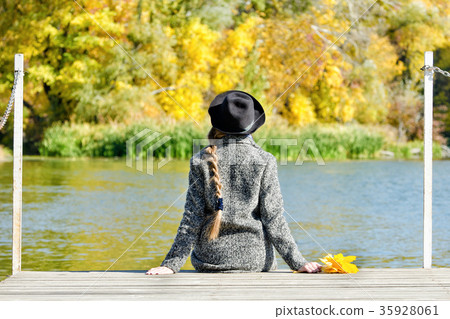 Girl in the hat sitting on the dock. Autumn forest 35928061