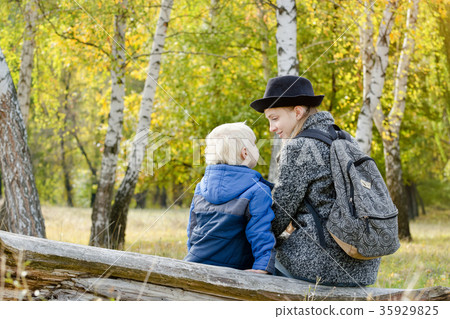 Mom and son are sitting in the autumn forest 35929825