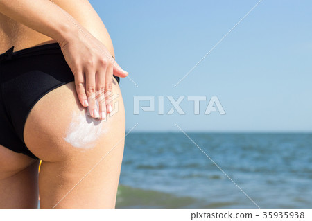 girl applying suntan lotion on her buttocks 35935938