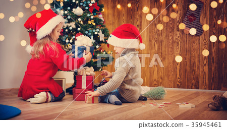Boy and girl lying on the floor with presents near 35945461