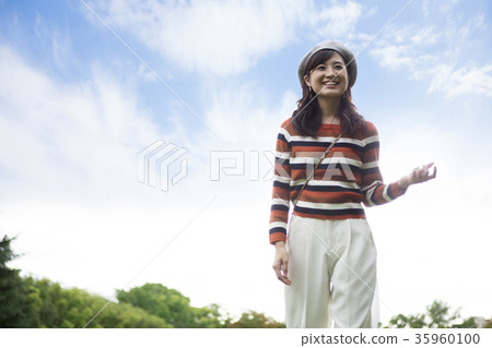 Woman taking a walk in the park under blue sky 35960100