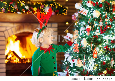 Child at Christmas tree and fireplace on Xmas eve 35968547