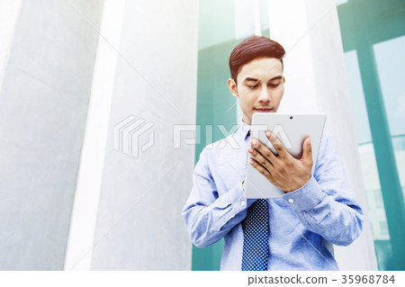 Young Businessman Reading or Working on Tablet Young Businessman Reading or Working on Tablet 35968784