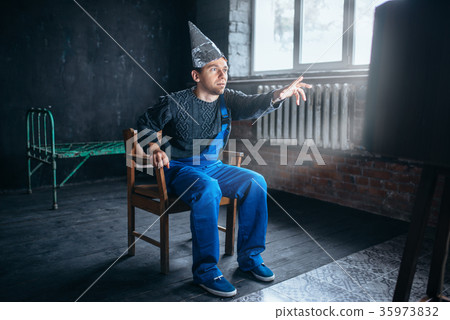 Man in aluminum foil helmet reaches out to the TV 35973832