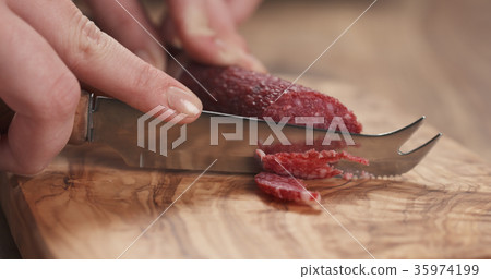 closeup female slicing thin salami sausage 35974199
