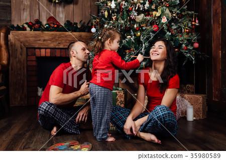 The family in pajamas plays next to a Christmas The family in pajamas plays next to a Christmas 35980589
